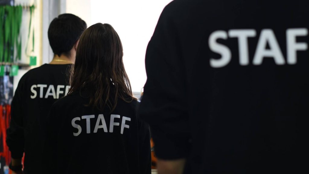 Tre persone che indossano una maglietta con la scritta STAFF sulla schiena