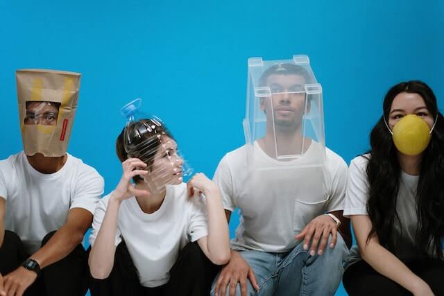 Un'immagine di quattro attori impegnati nell'improvvisazione, ognuno con un oggetto unico sulla testa, che mostra la loro creatività e spontaneità nella performance teatrale.